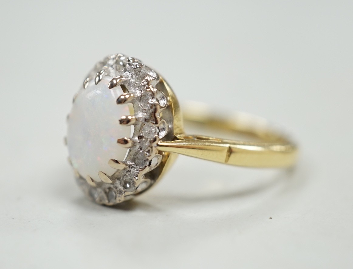 A modern 18ct white gold white opal and diamond set oval cluster ring, size M, gross weight 4.3 grams.